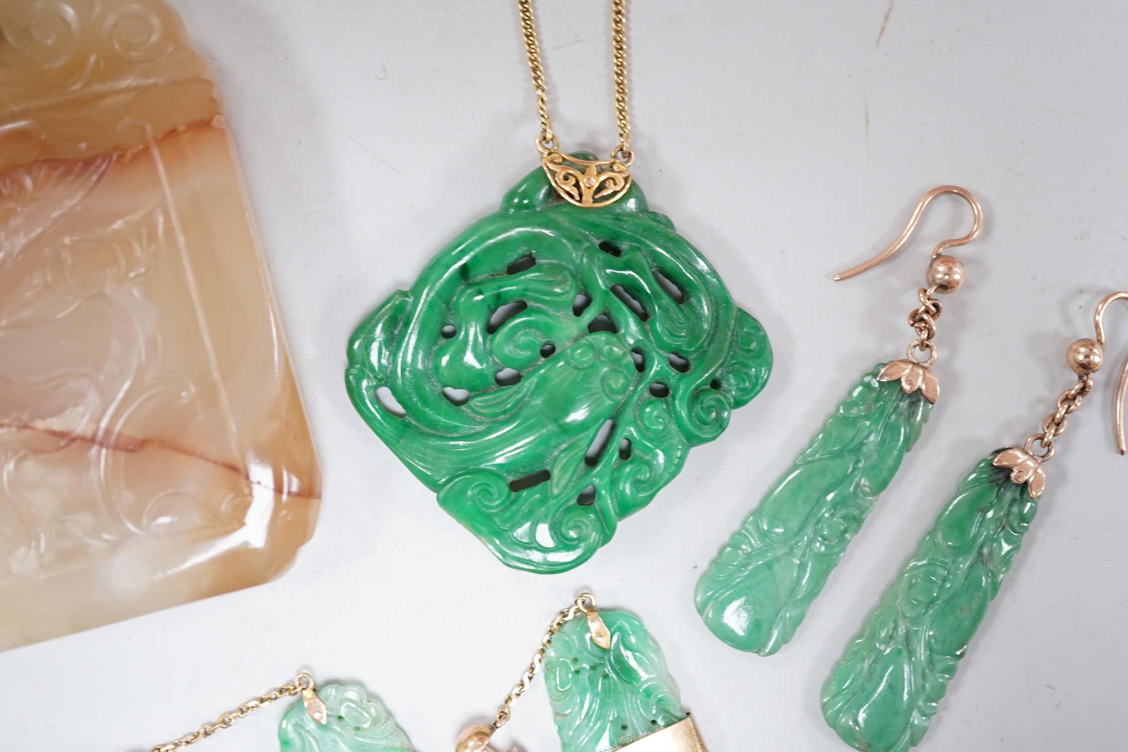 A Chinese carved hardstone pendant, 64mm, a pierced green hardstone pendant on chain and two pairs of yellow metal mounted carved jade earrings.